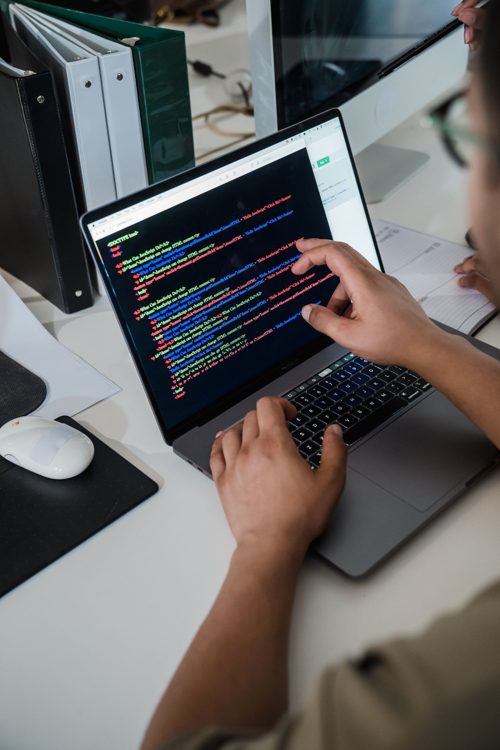 A person pointing at structured code on a laptop screen, representing information architecture and structuring digital products