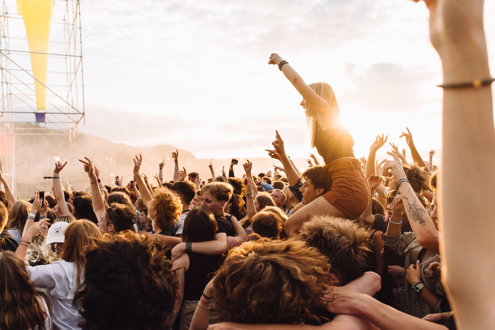 Outdoor festival crowd with hands raised at sunset, showing the audience journey across the event's travel phases