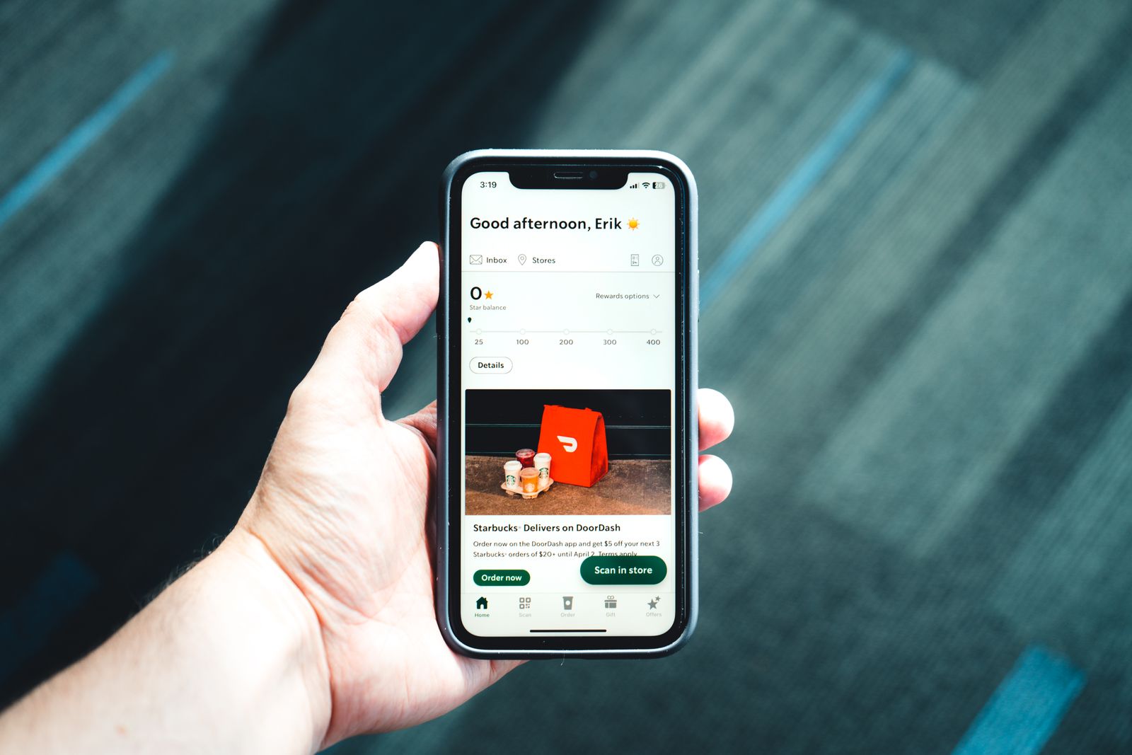 Hand holding a smartphone showing a booking and delivery app interface, representing a ticketing UX redesign