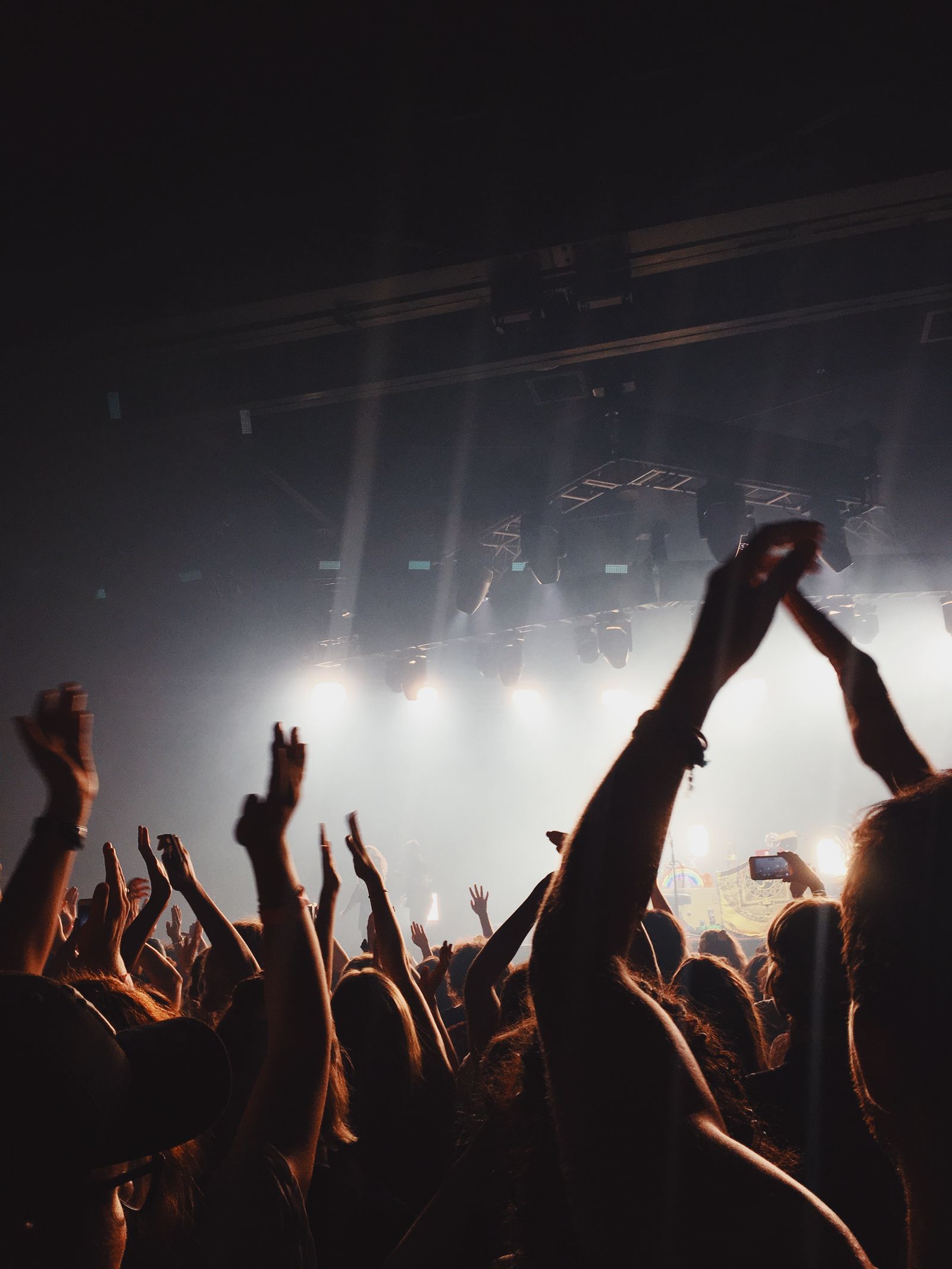 Indoor concert audience facing a brightly lit stage, illustrating the divide between the artistic team and the rest of the event journey