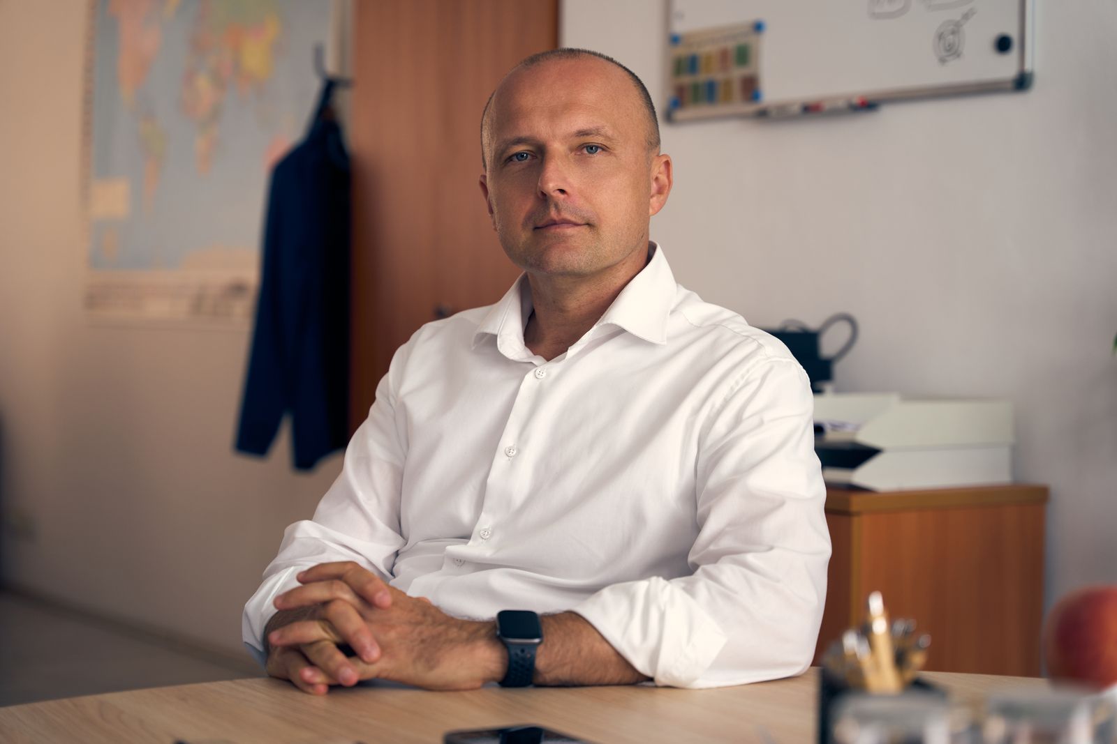 Professional in a well-lit modern office with a thoughtful expression, representing the UI/UX designer role
