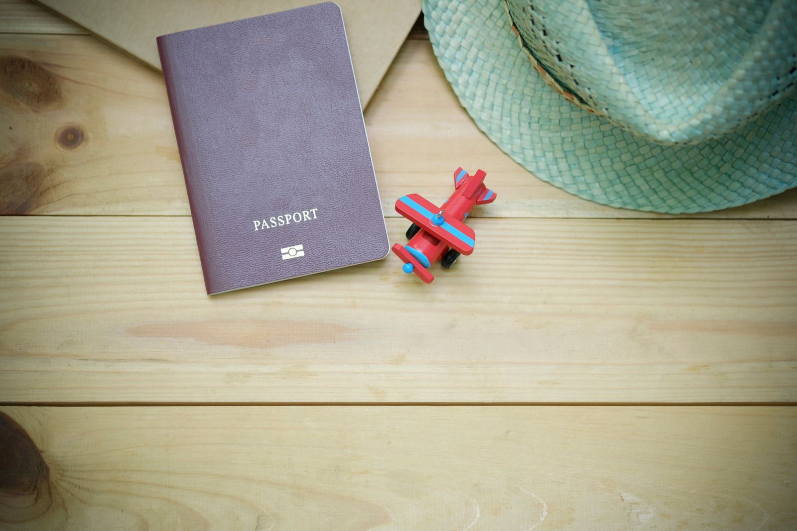 A passport with a straw hat and toy aeroplane, representing the Subclass 482 sponsorship visa and relocation