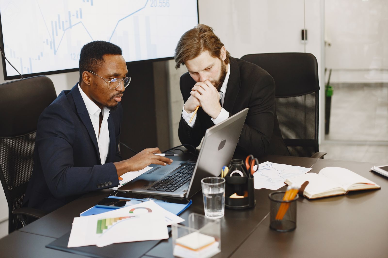 Two professionals reviewing charts and laptops in a strategy meeting, representing UX governance