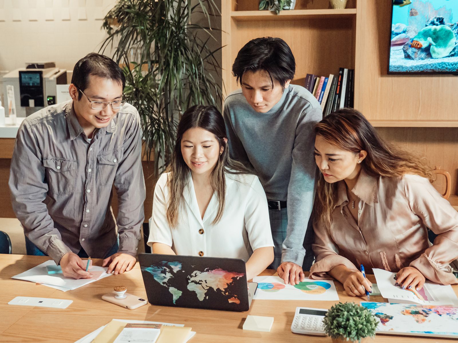 Diverse team collaborating over a laptop in a meeting, representing the many distinct UX and product roles