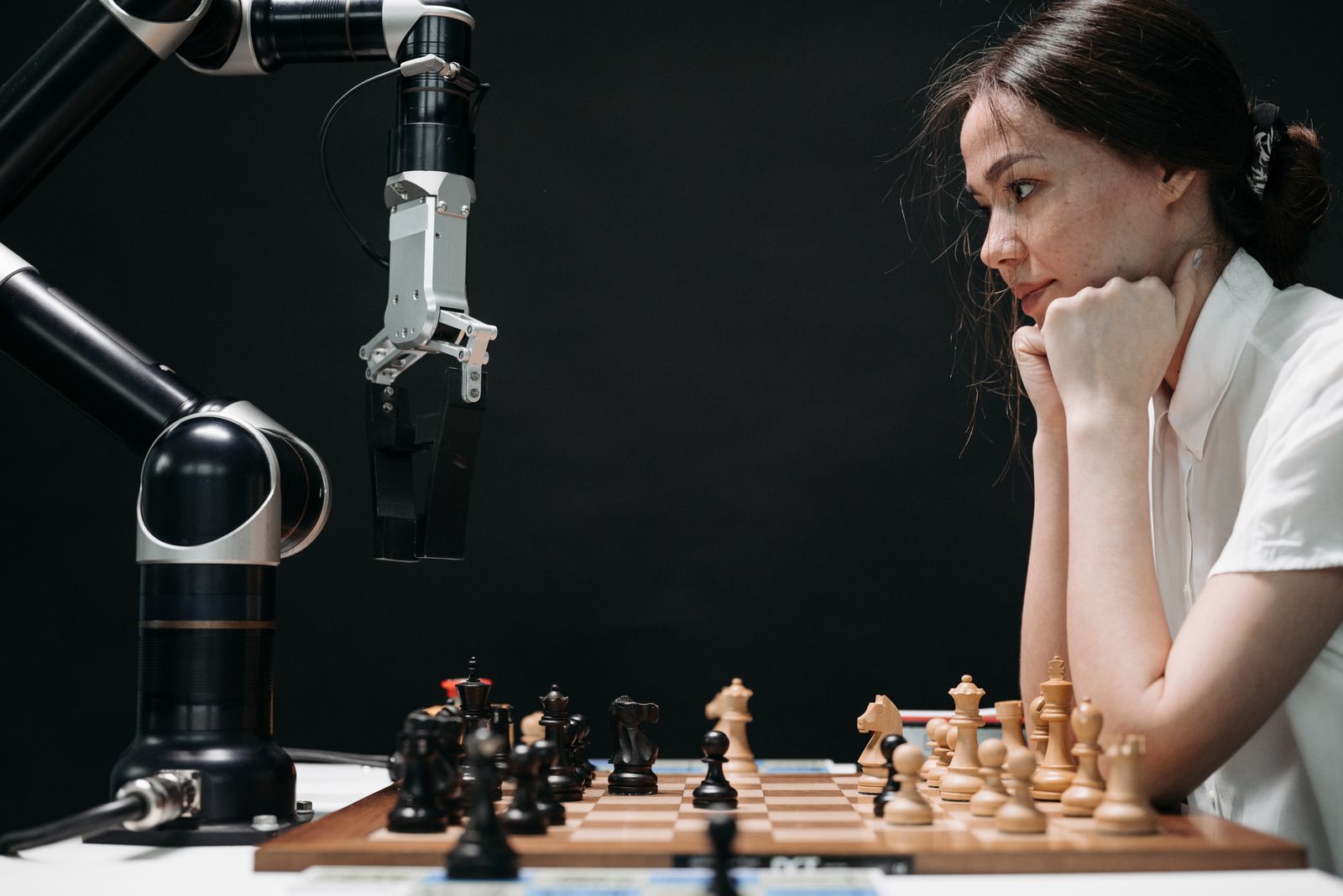 A person strategising a chess game against a robotic arm, representing SMEs competing with larger firms using AI