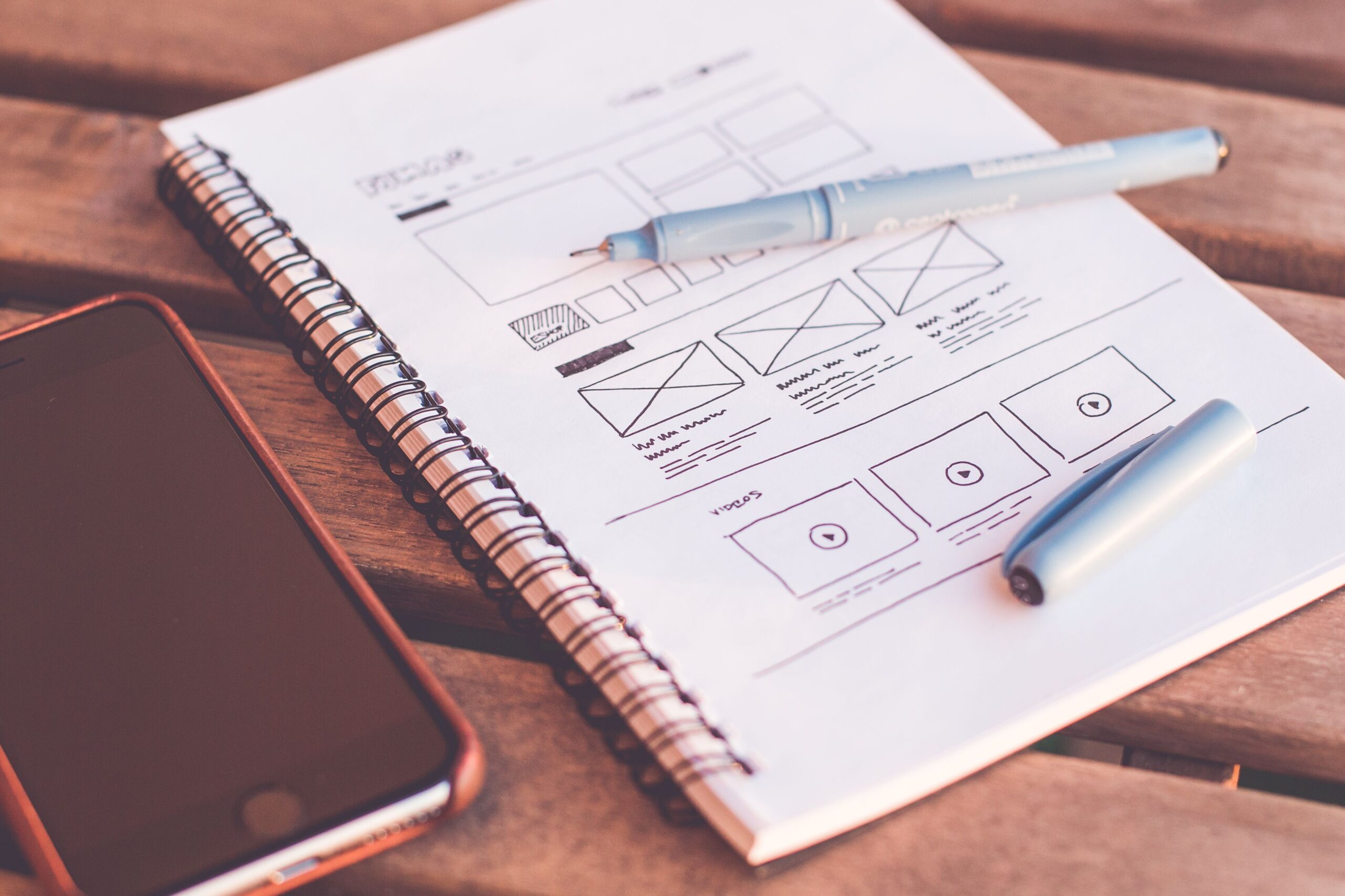 Designer sketching colourful mobile app wireframes on paper representing design systems and design-engineering collaboration